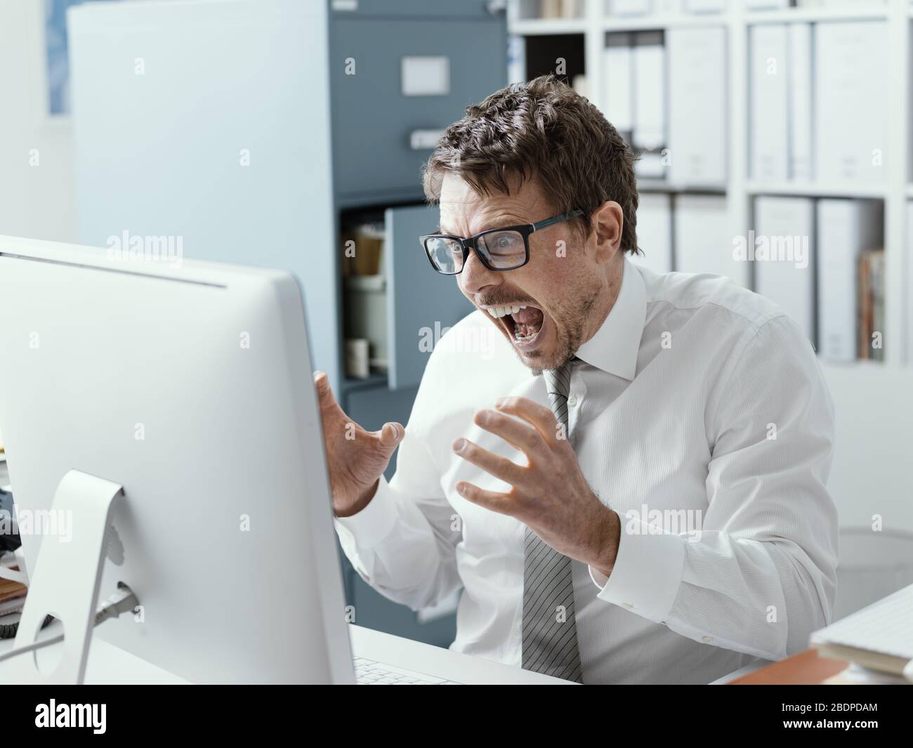 Angry business executive shouting at the computer, stressful job and system failure concept Stock Photo