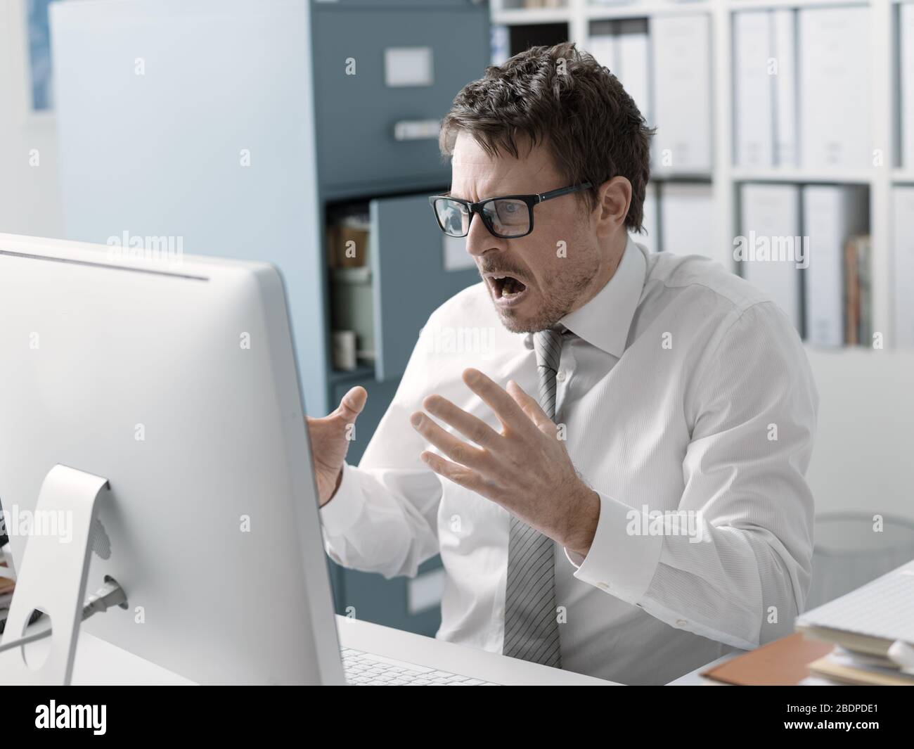 Angry business executive shouting at the computer, stressful job and system failure concept Stock Photo