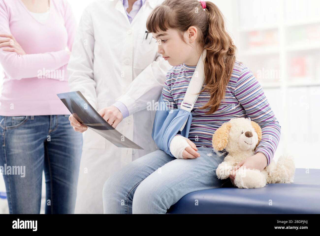 Friendly female doctor showing an x-ray image to a young patient with broken arm, healthcare and children concept Stock Photo