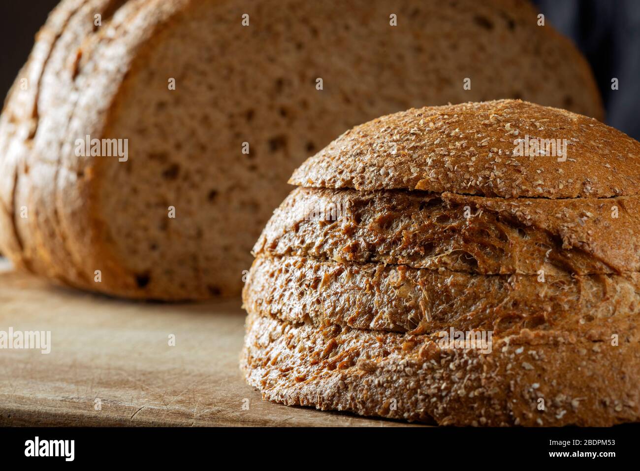 Slices of borwn bread on a wooden cutting board Stock Photo