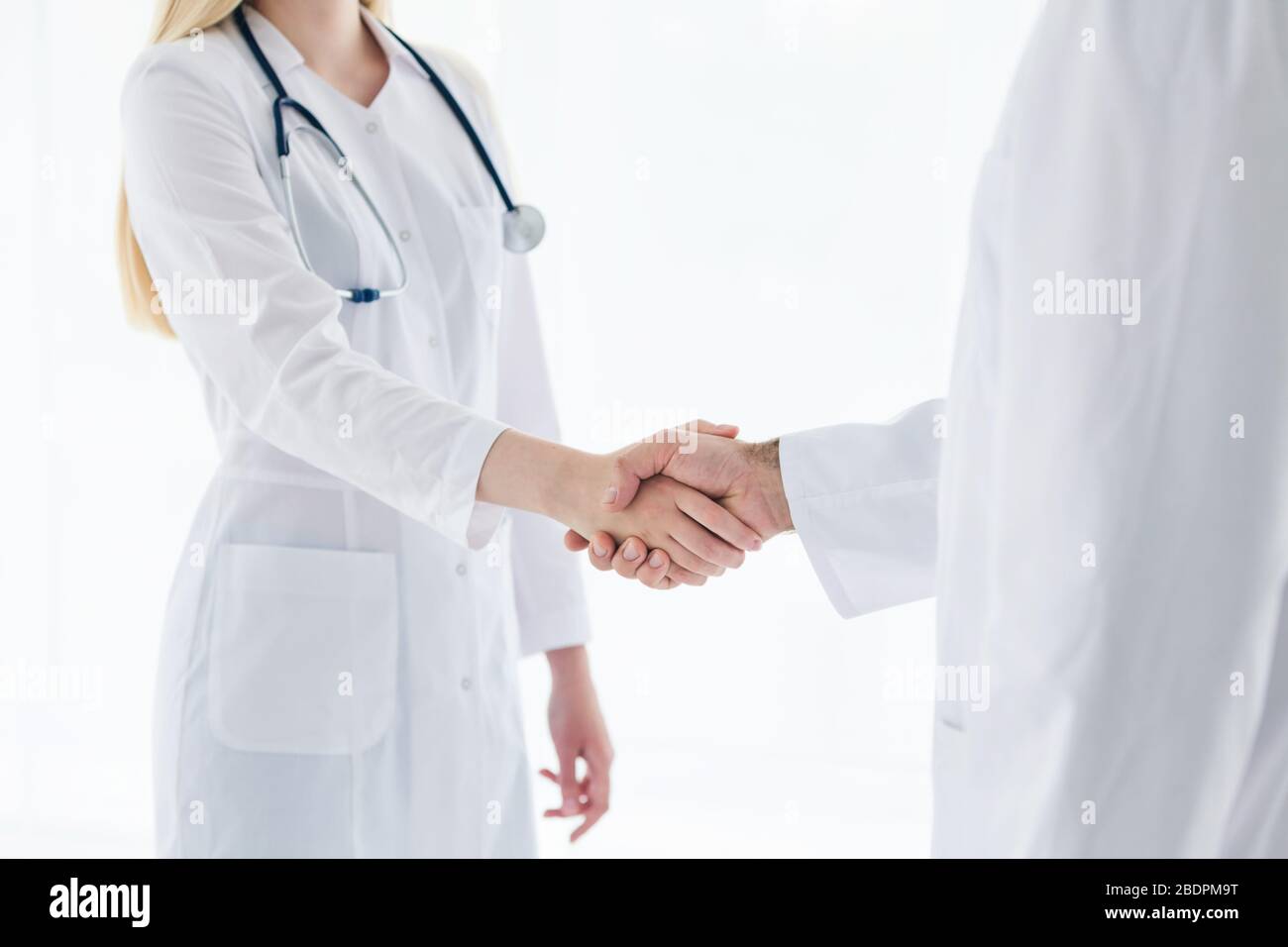 Doctors in lab coats greeting each other with handshake Stock Photo
