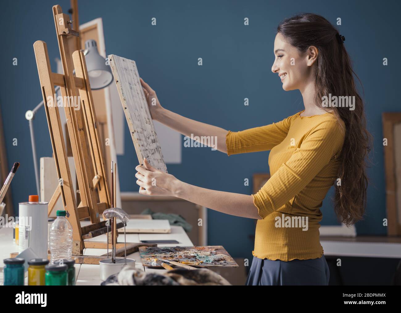 Young artist putting a canvas on the easel and checking her painting ...