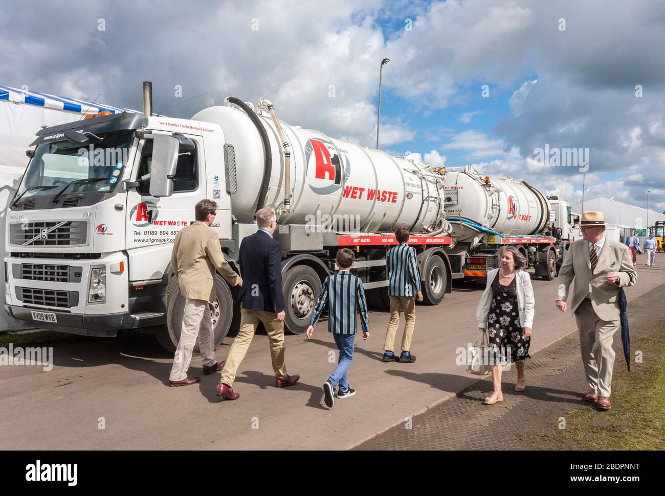 Festival goers walk past wet waste lorries at Henley Royal Regatta, Henley-on-Thames, Oxfordshire, England, GB, Uk. Stock Photo