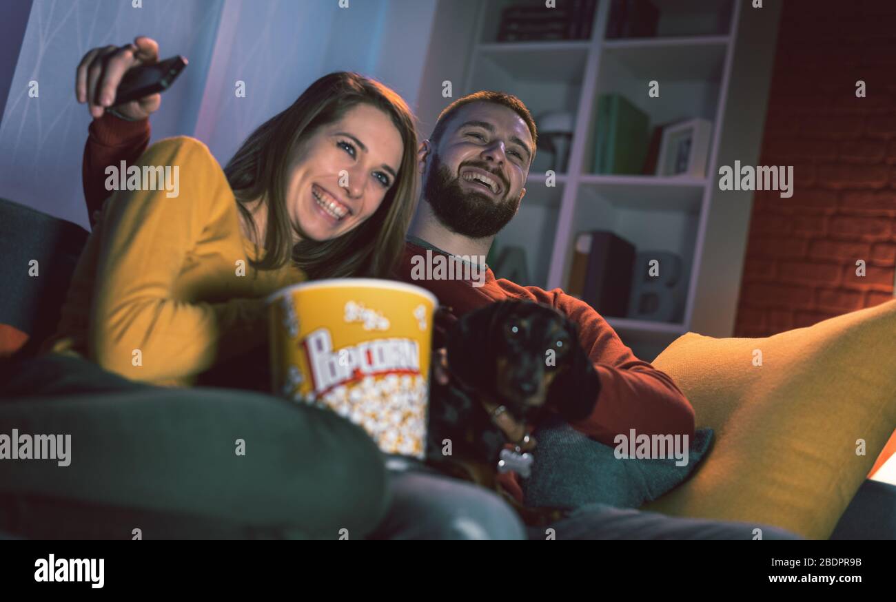 Happy couple relaxing on the sofa at home with their dog they are