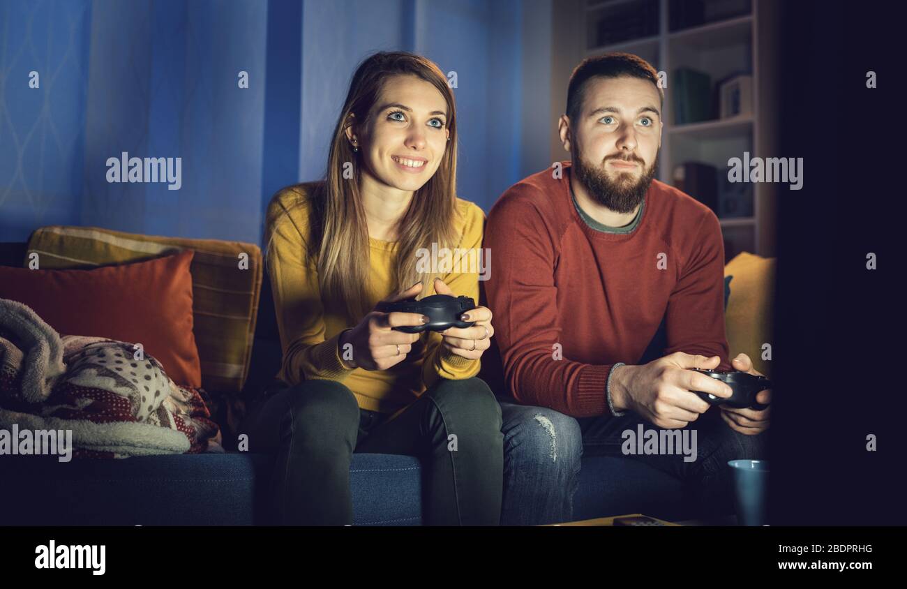 Happy Couple Sitting On The Sofa Playing Video Games Using