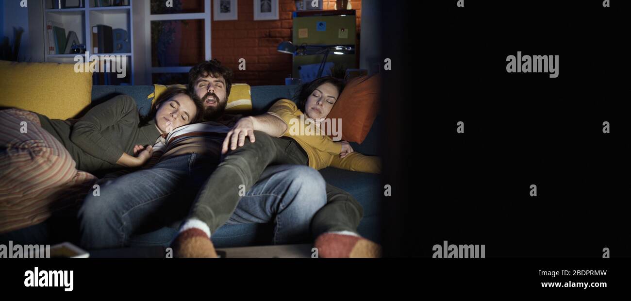 Friends falling asleep on the sofa at home while watching TV at night