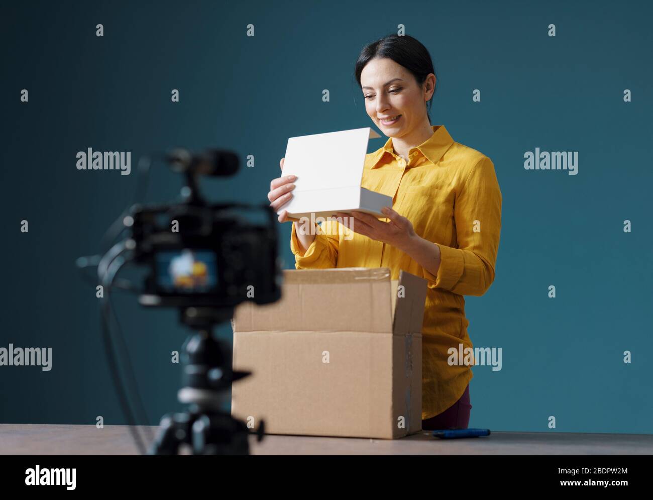 Vlogger making a unboxing video for her channel, she is opening a delivery box Stock Photo