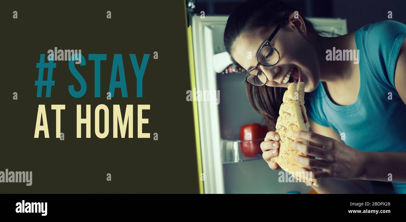 Humorous Coronavirus stay at home social media awareness campaign: hungry woman eating unhealthy food and coping with stress Stock Photo