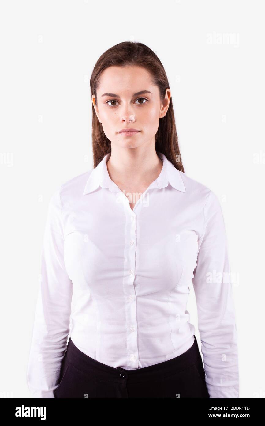 Girl with brown hair, clear skin in white shirt stands straight
