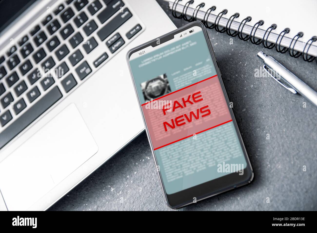 Laptop and smartphone with 'fake news' alert on the screen. Conception of increasing level of fake news. Stock Photo