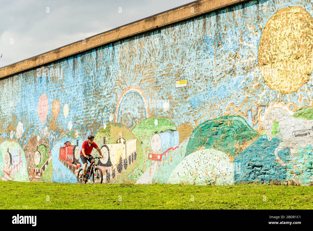 Cyclist passes railway mural at Great Harwood, Lancashire, part of the Hyndburn Greenway Stock Photo
