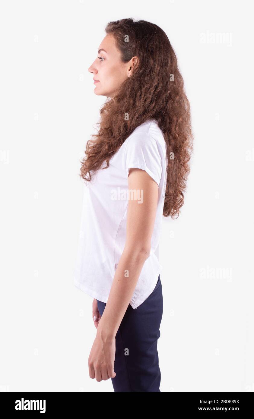 Slim girl stands sideways to camera and looks straight ahead. White ...