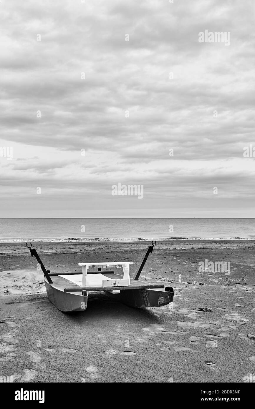 Safety boat - catamaran by the sea on empty beach in Rimini at off-season, Italy - Minimalistic landscape, black and white photography Stock Photo