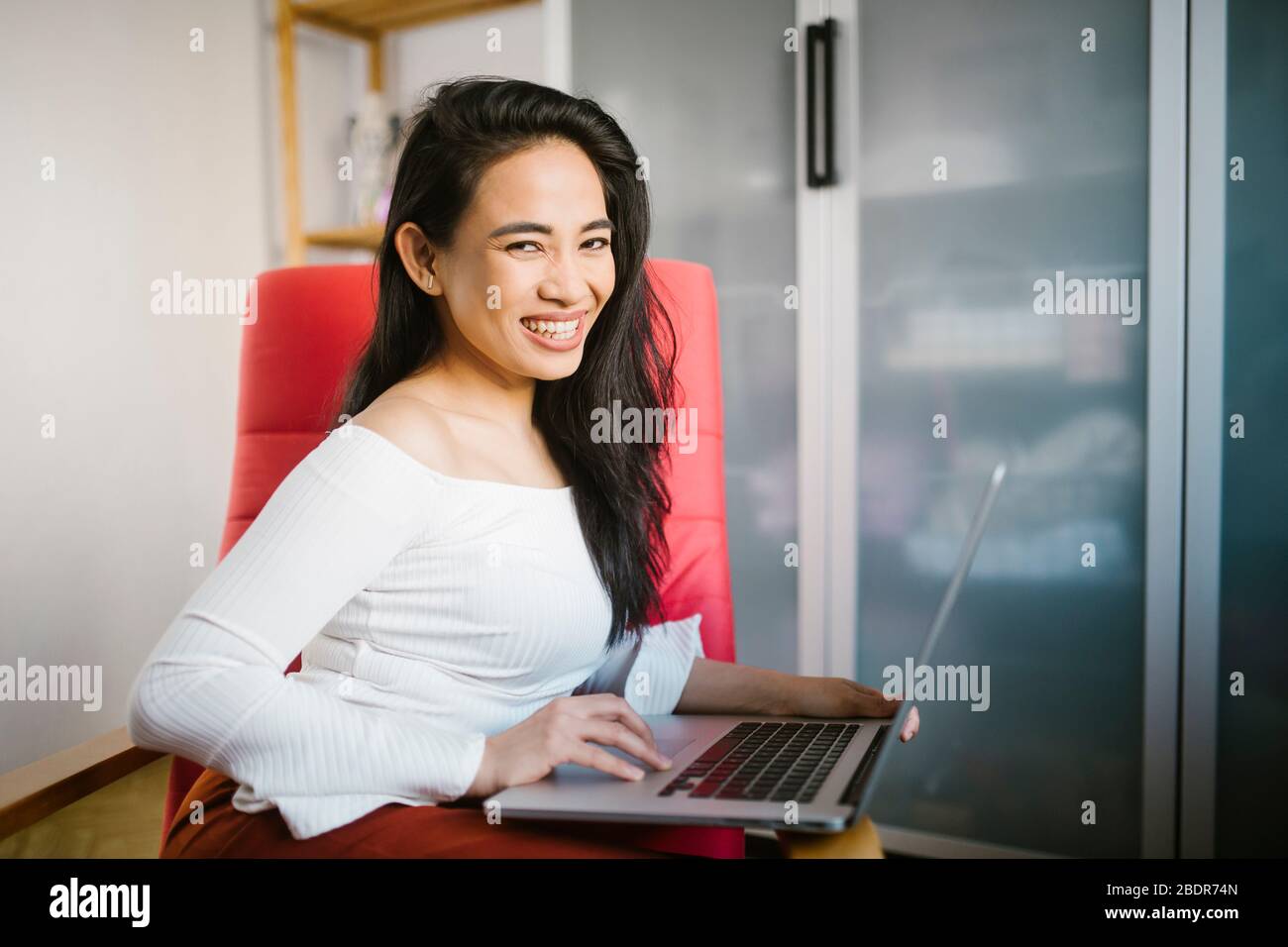 Beautiful young woman working from home with a laptop computer on her laps Stock Photo