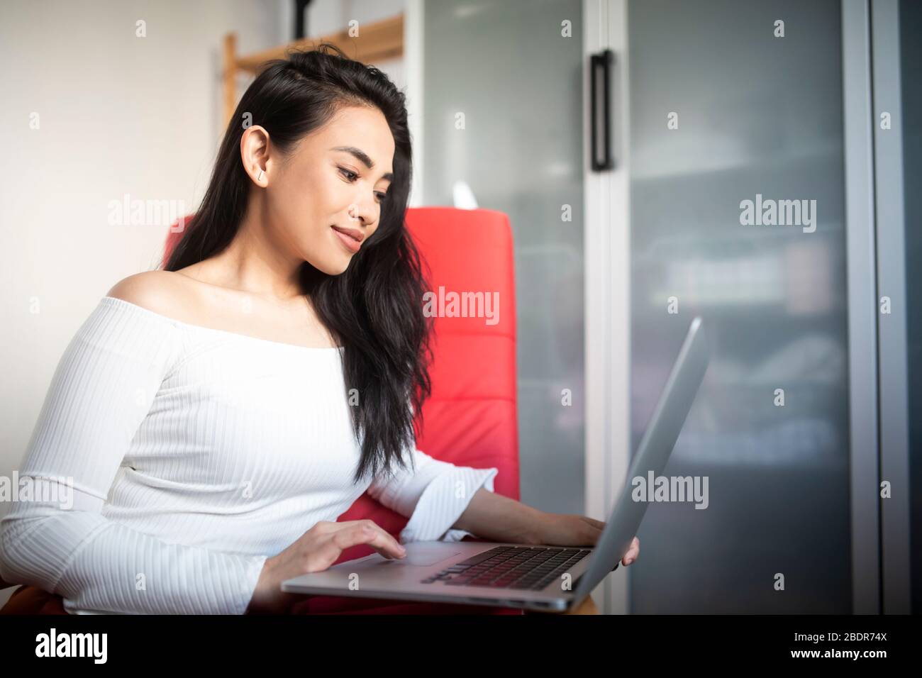 Beautiful young woman working from home with a laptop computer on her laps Stock Photo