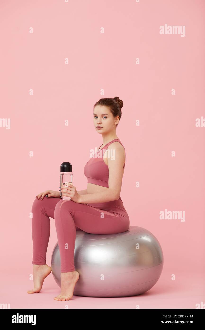 Portrait of a fit beautiful young woman sitting on exercise ball in ...