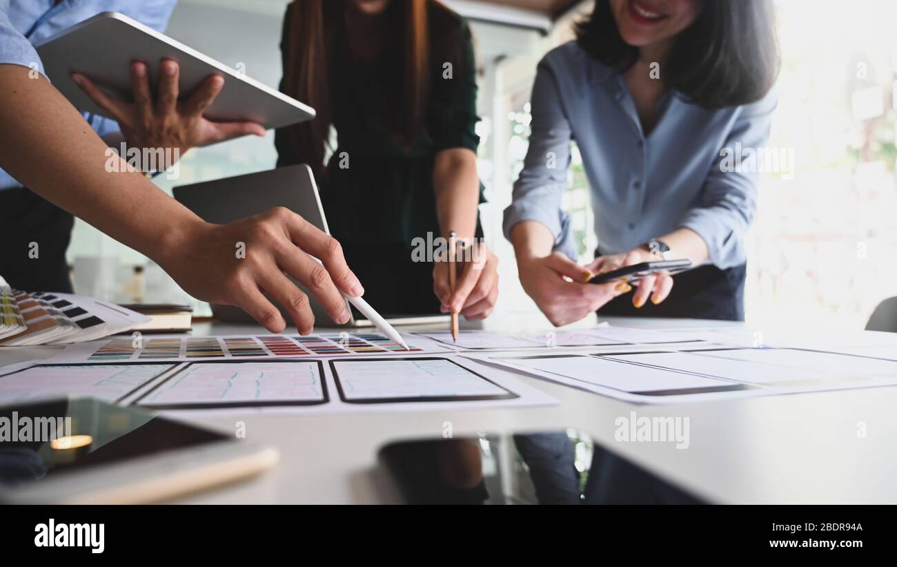 Photo of UxUi development team discussing/meeting/talking about their business concept by using a computer tablet, laptop and mobile at the modern mee Stock Photo