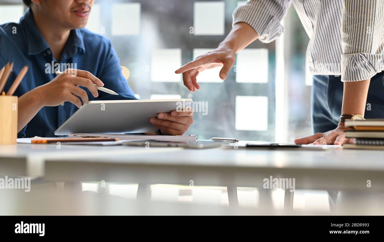 Business development team while discussing/meeting at the modern meeting table with computer tablet and document. Comfortable workplace concept. Stock Photo