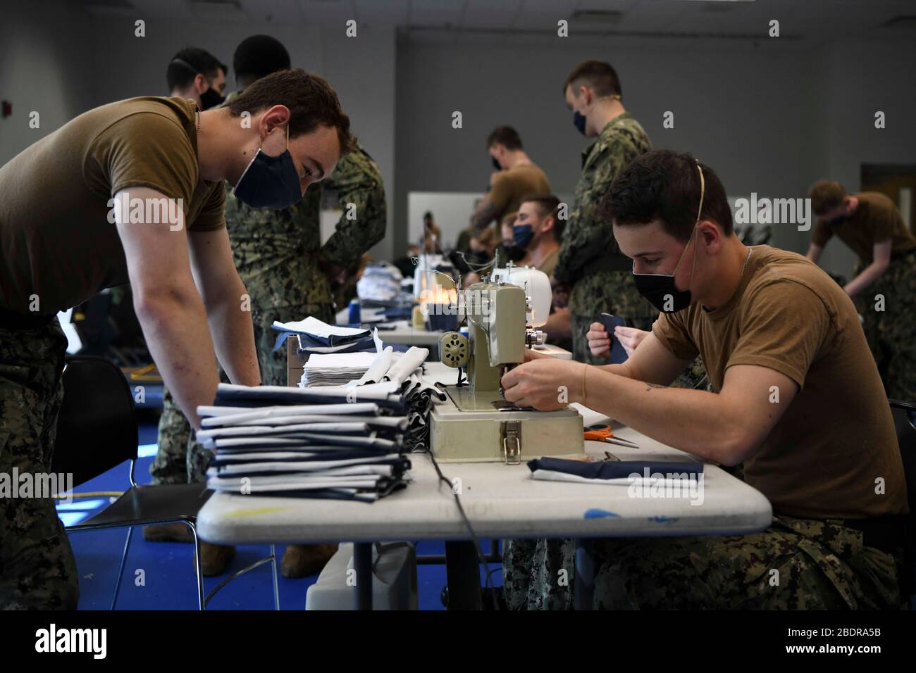 U.S. Navy sailors sew fabric for cloth masks at the Naval Nuclear Power Training Command April 8, 2020 in Goose Creek, South Carolina. Sailors are now required to wear masks when social distancing may not be possible to help mitigate the spread and prevent COVID-19. Stock Photo