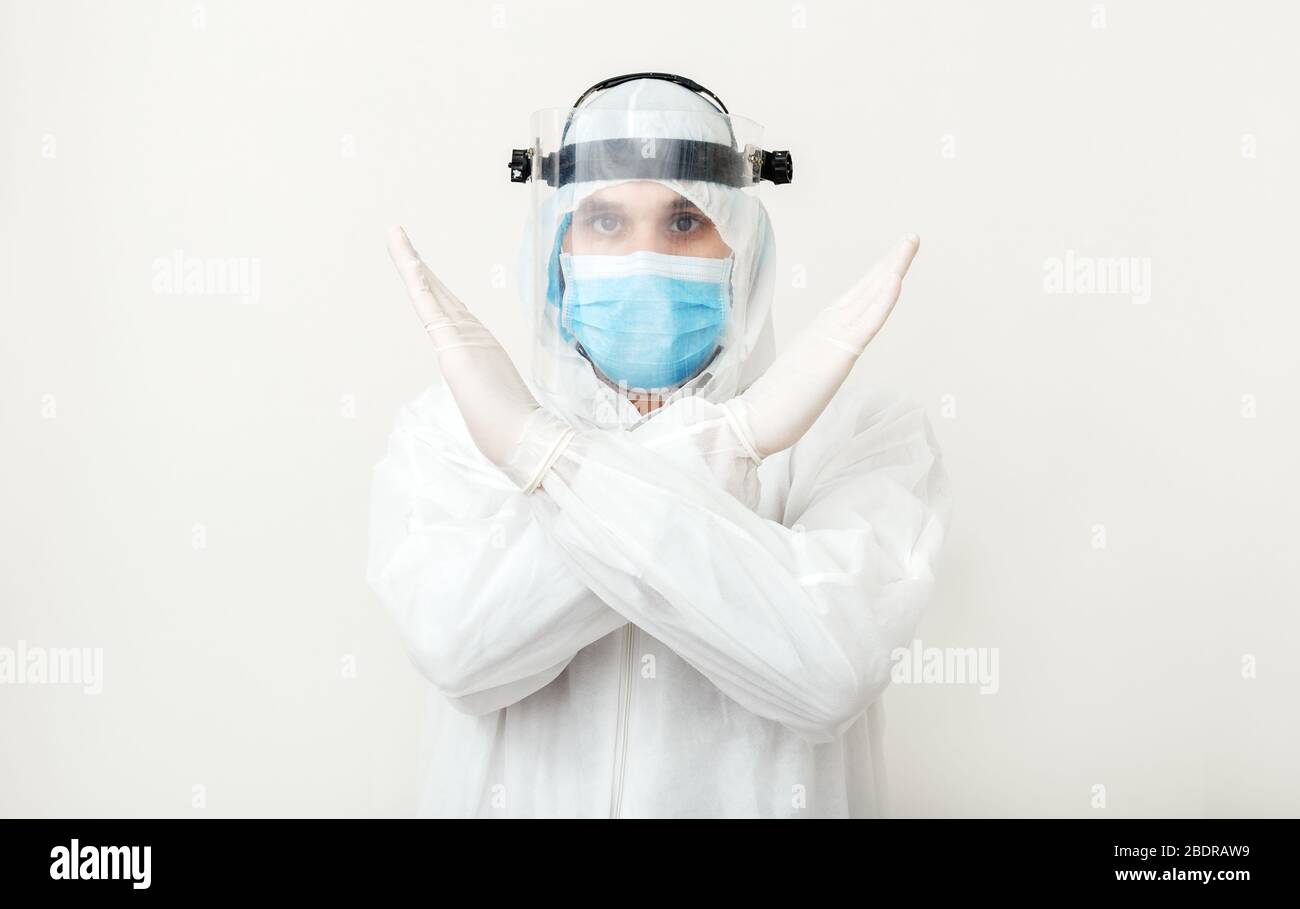 Doctor wearing protection suit and face mask show sign gesture stop pandemic epidemic of Covid-19, Coronavirus on white background. Concept of Stock Photo
