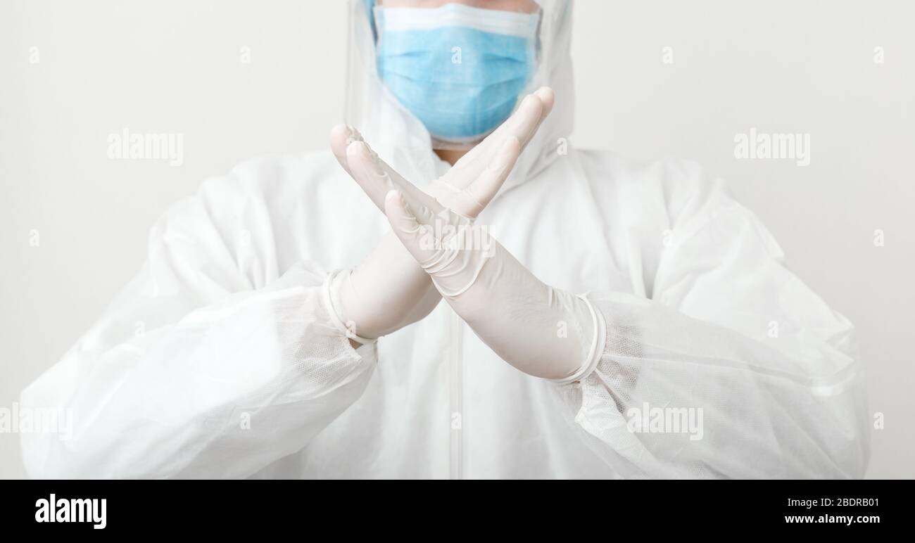 Doctor wearing protection suit and face mask show sign gesture stop pandemic epidemic of Covid-19, Coronavirus on white background. Concept of Stock Photo