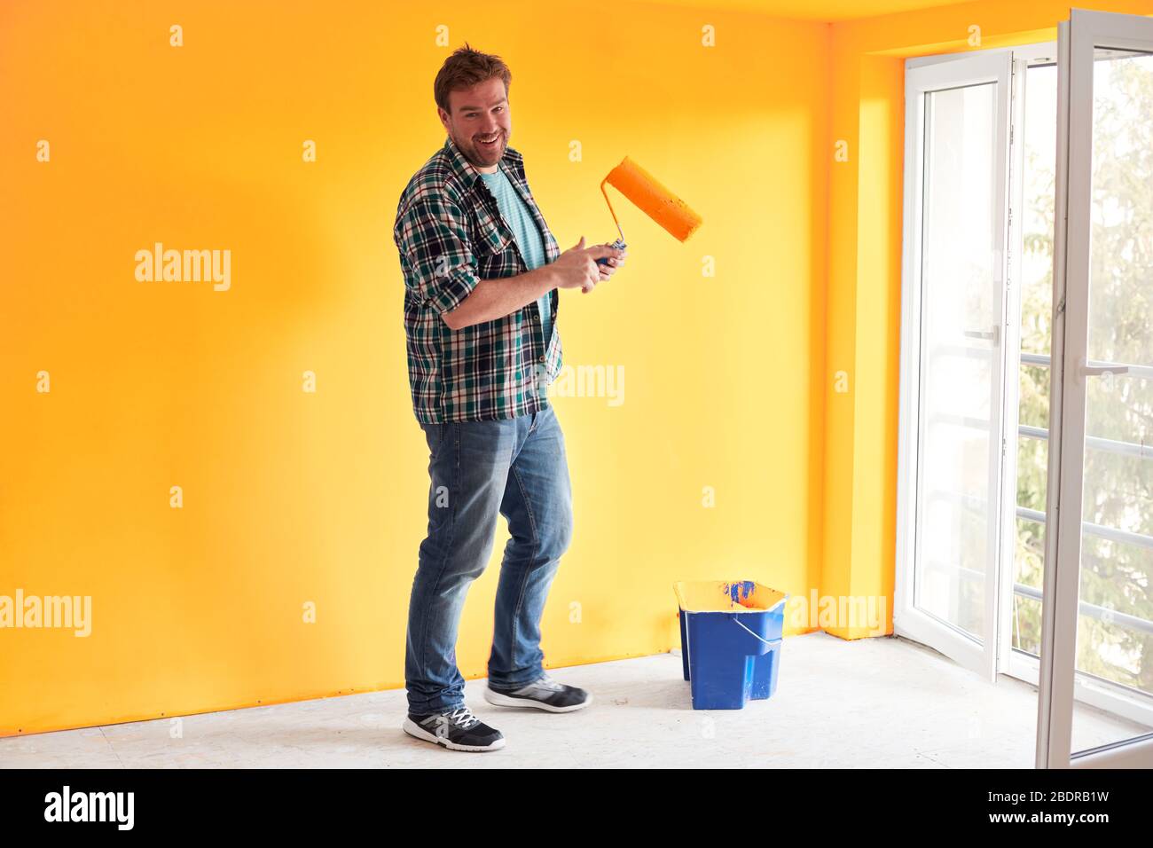 Young man painting a wall on sunflower color in a modern home Stock Photo