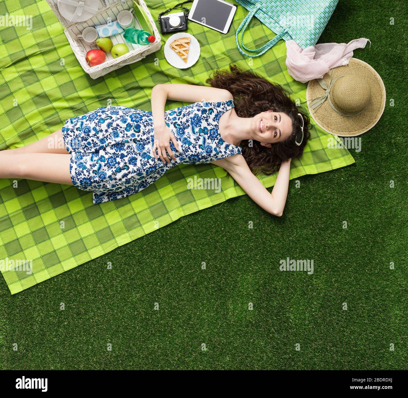 Young smiling woman relaxing outdoors and having a picnic, she is lying