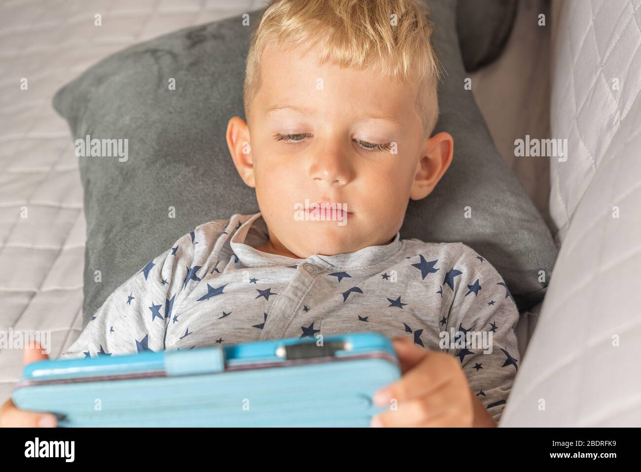 Caucasian baby boy using digital tablet while lying on bed at home Stock Photo