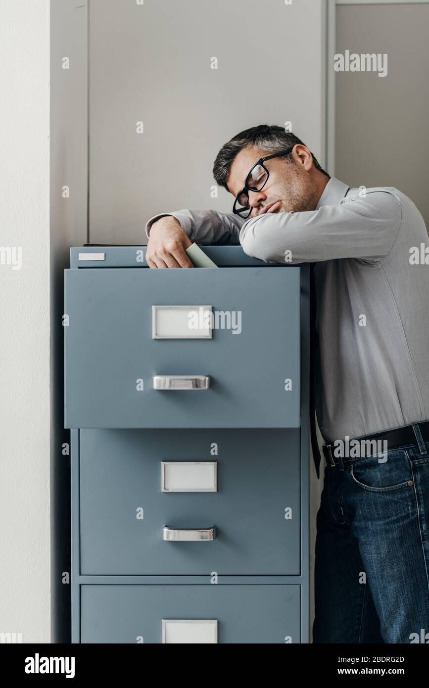 Tired lazy office worker leaning on a filing and sleeping, he