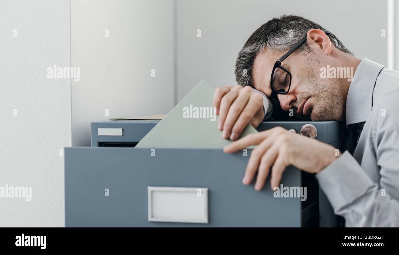 Tired lazy office worker leaning on a filing and sleeping, he