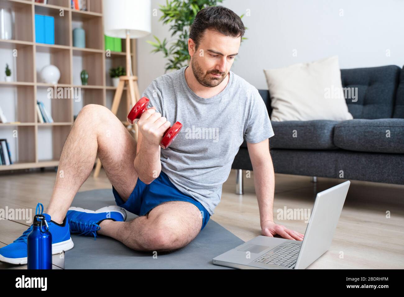 Man doing home work out while watching tutorial on laptop Stock Photo