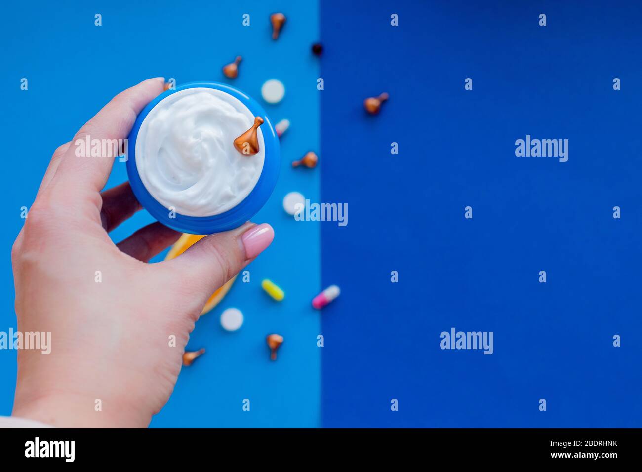 Golden cosmetic capsules with face and eyelid cream isolated on blue