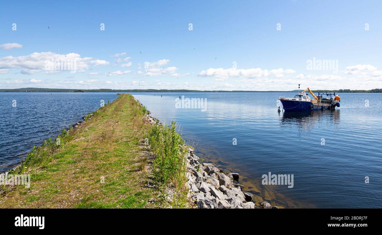 Small inland lake fishing trawler anchored behind a breakwater at lake Pohjois-Konnevesi , Finland Stock Photo