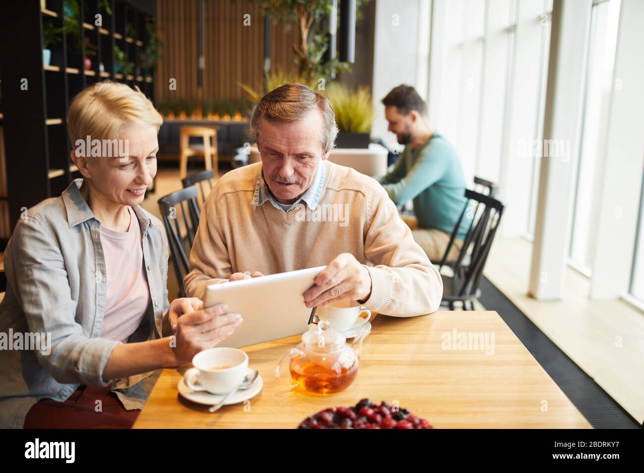 Mature couple using digital tablet while drinking tea at the table in the restaurant Stock Photo