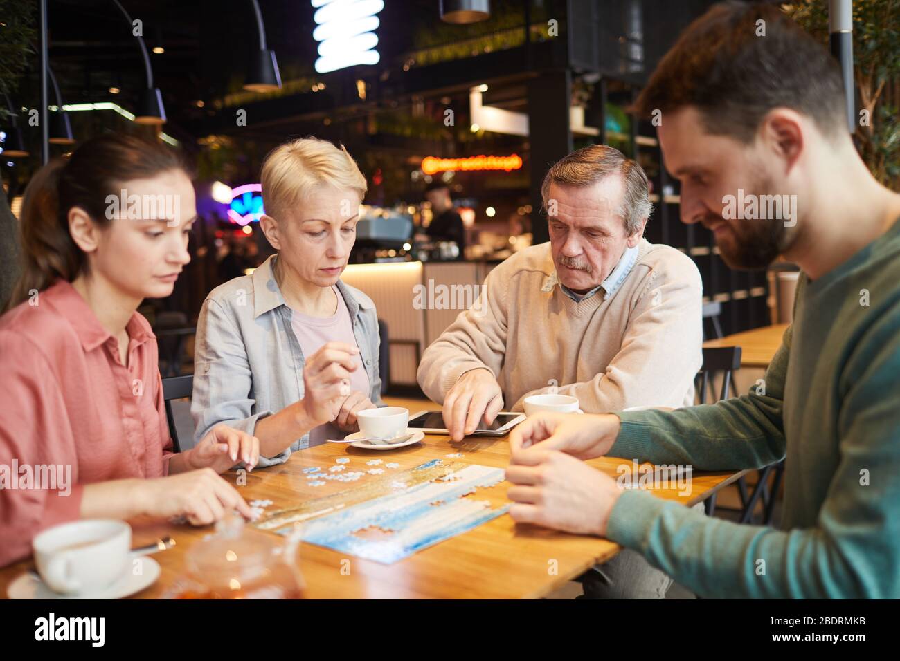 Mature parents with their adult children playing in board game together