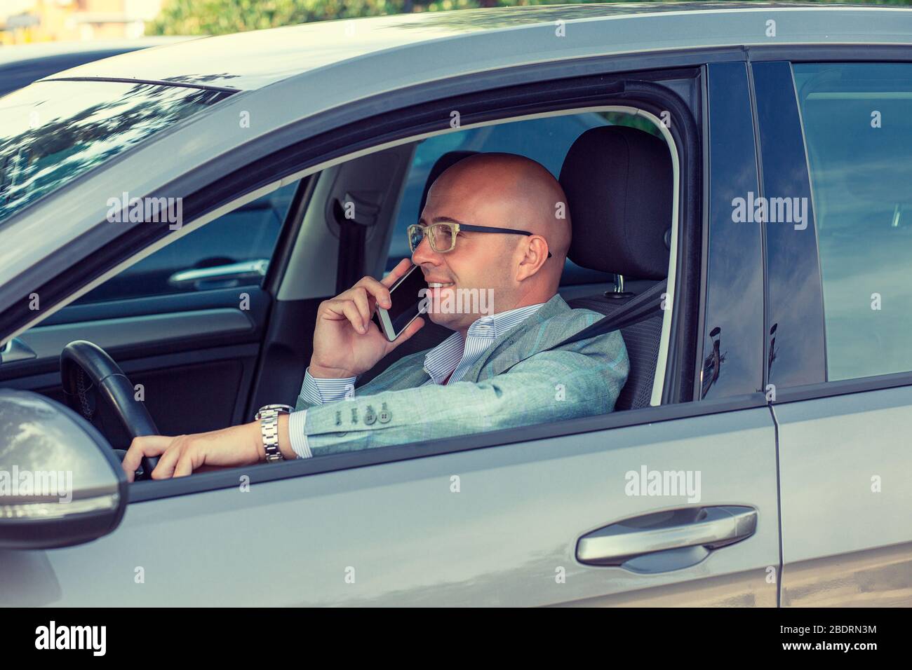 Young handsome businessman using mobile phone while driving car to work