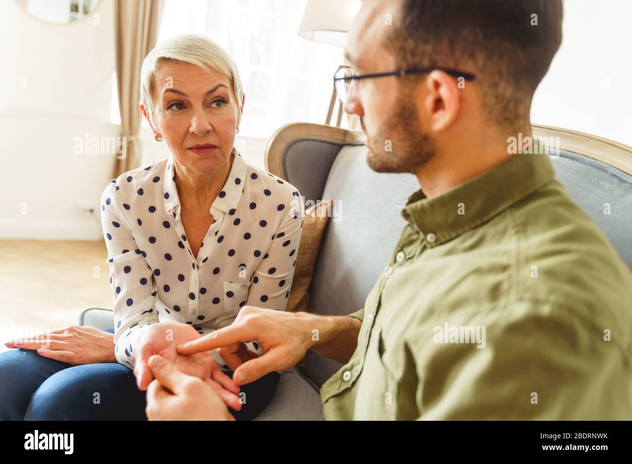 Modern palm reader holding his clients hand Stock Photo
