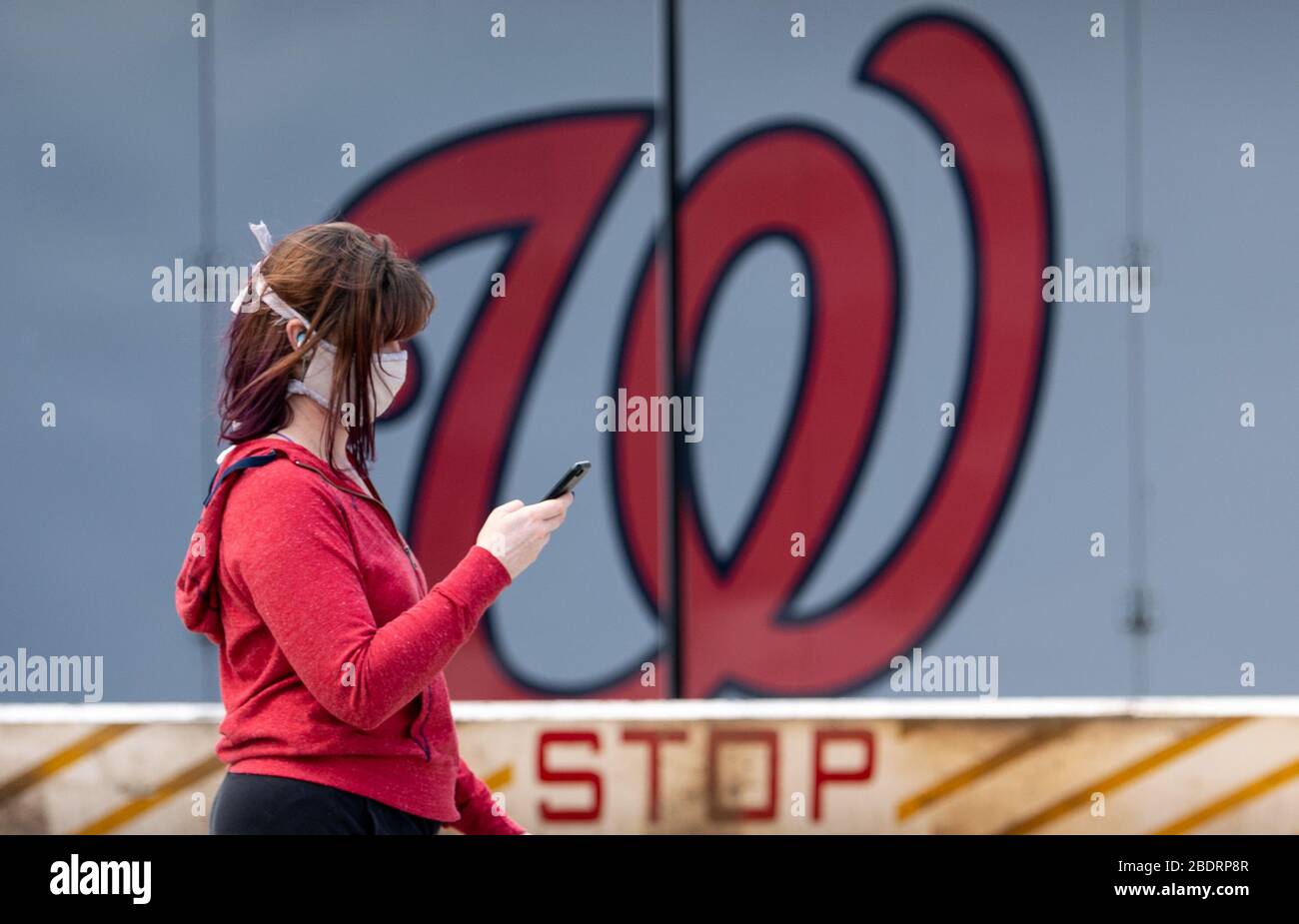 Washington, United States. 09th Apr, 2020. A person wearing a mask walks past a Washington Nationals logo at Nationals Park in Washington, DC on Thursday, April 9, 2020. World Central Kitchen is using Nationals Park to prepare and distribute food to agencies that help needed individuals during the Coronavirus pandemic. Photo by Kevin Dietsch/UPI Credit: UPI/Alamy Live News Stock Photo