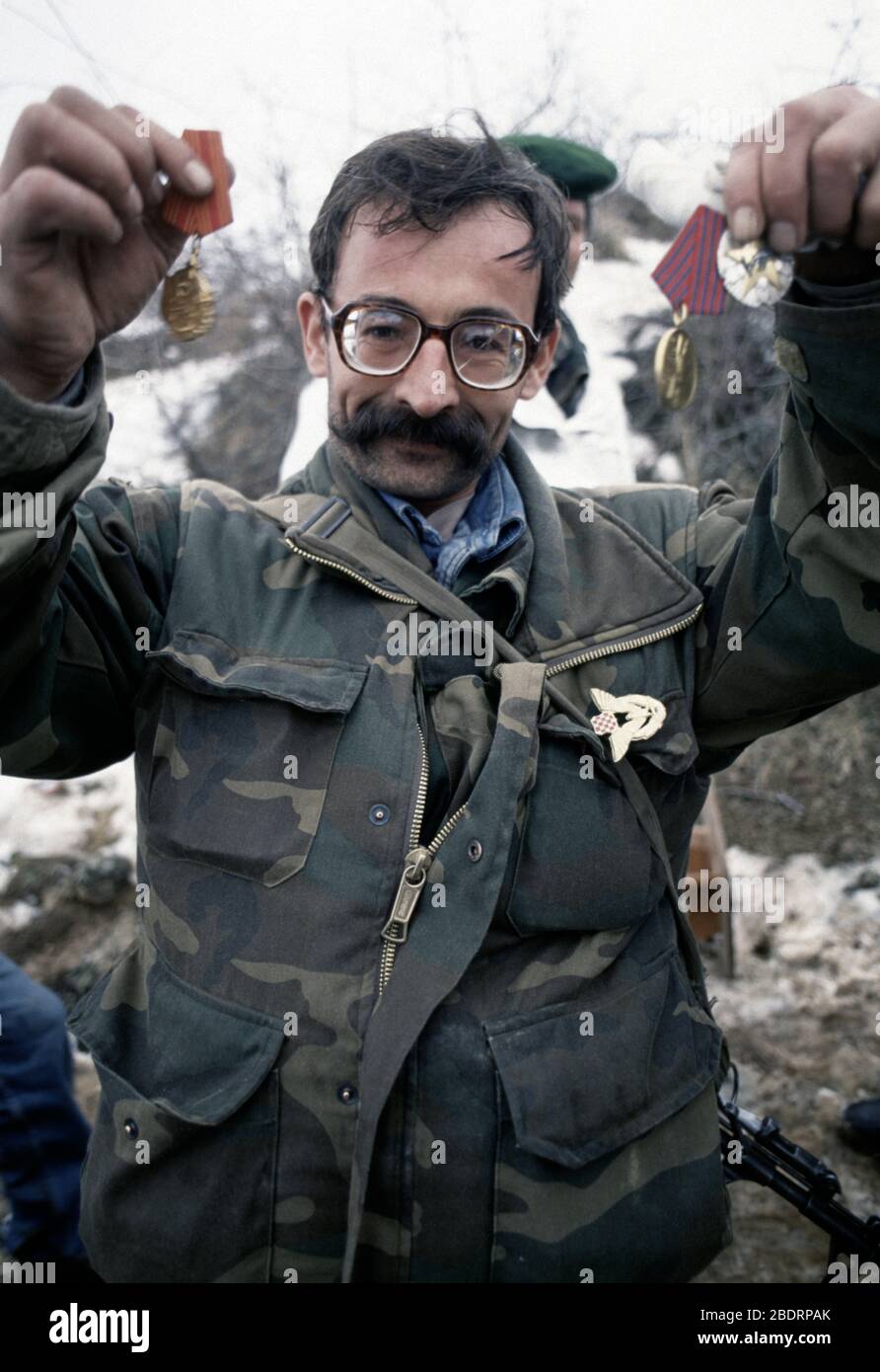 26th January 1994 During the war in central Bosnia: a victorious soldier of the HVO's Rama Brigade holds up military medals in the Bosnian Muslim village of Here, which was captured two days before. Stock Photo
