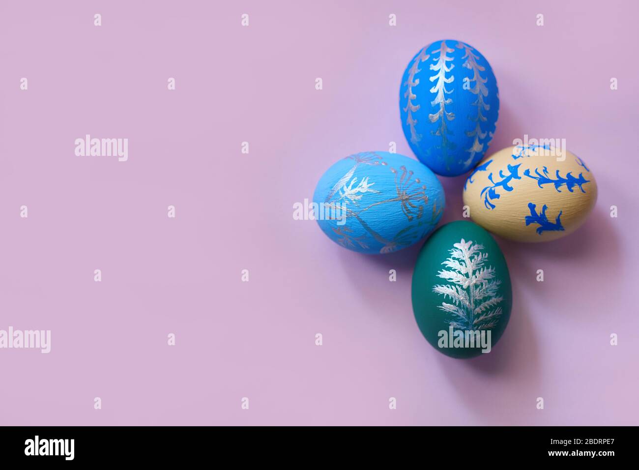 four colored easter eggs on a pink background top view. horizontal image with copy space. Stock Photo