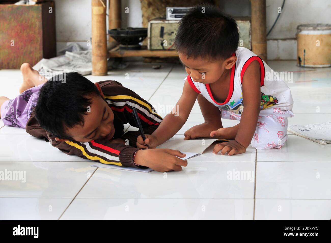 Bali, Indonesia - January 24, 2009: Children of an Indonesian artist paint while sitting on the floor. Bali is famous for talented artists. Bali, Indo Stock Photo