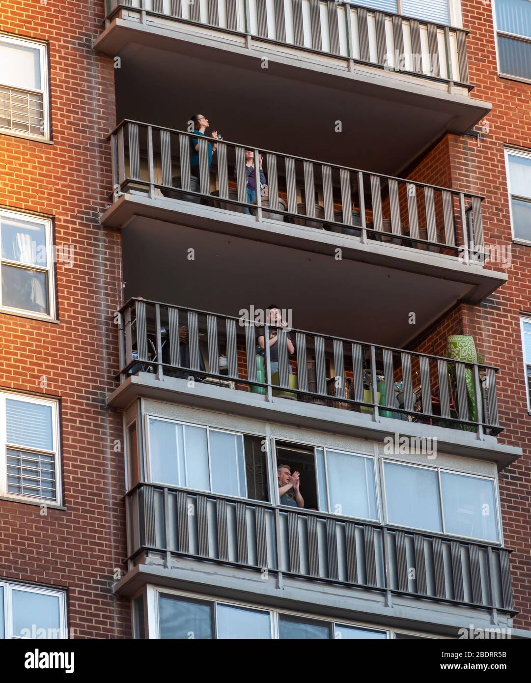 People applaud healthcare workers from their balconies in an apartment building in Chelsea in New York on Wednesday, April 8, 2020. At 7:00 PM every night New Yorkers scream, bang pots, blow whistles, etc. to make noise to show their support for healthcare workers on the frontlines in the COVID-19 pandemic. (© Richard B. Levine) Stock Photo