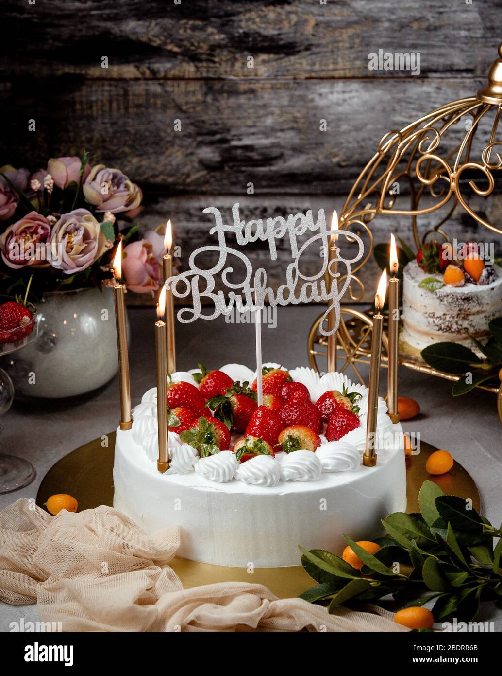 birthday cake with strawberries golden candles and happy birthday stand