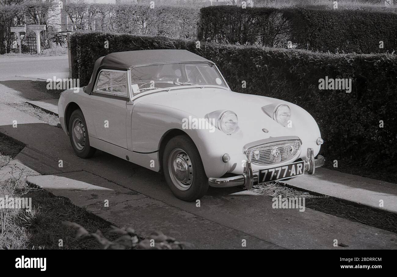 1960s, historical, Austin Sprite sports car parked beside a hedge on a narrow concrete driveway, Eastholm Green, England, UK. Stock Photo