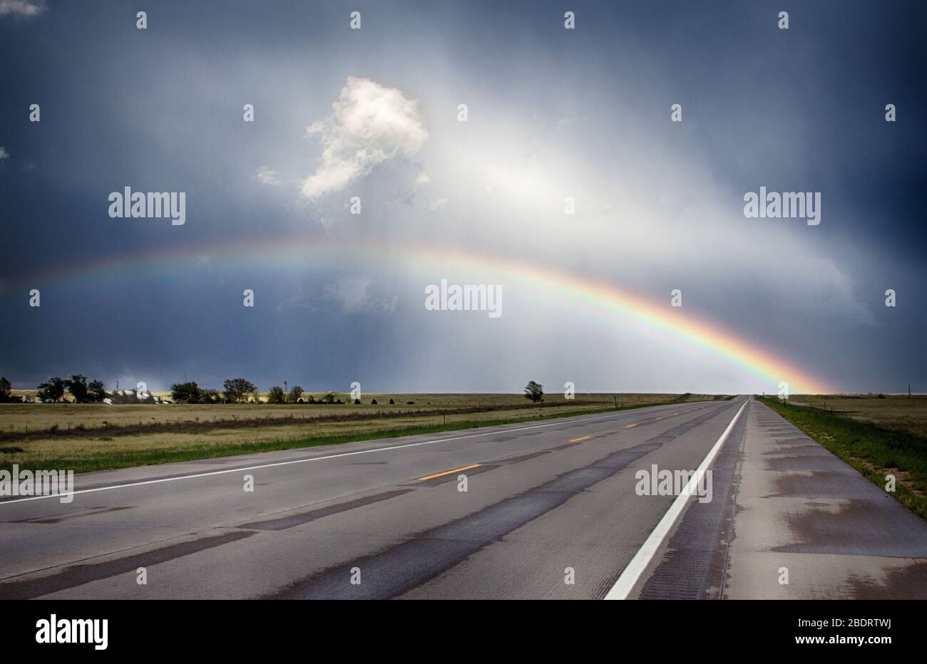 Rainbow over a road in Eastern Colorado Stock Photo