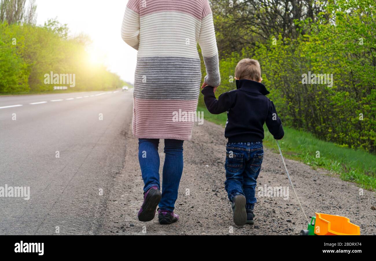 Morning walk. The child with his mother walking along the road to sunrise. Stock Photo