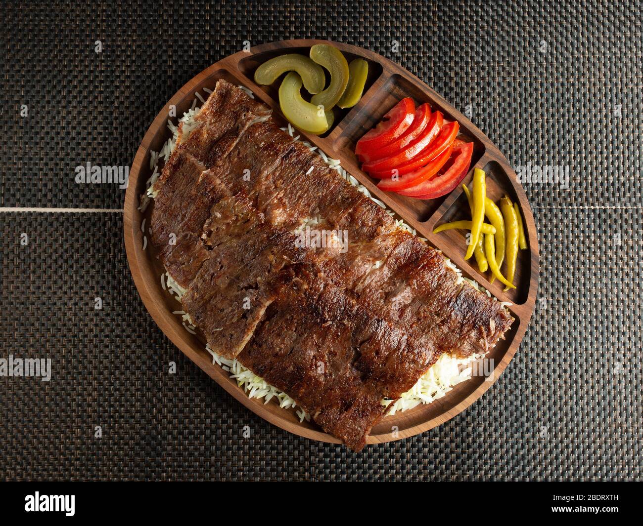 steak slices serve on rice with tomato slices pickled cucumbers and peppers Stock Photo