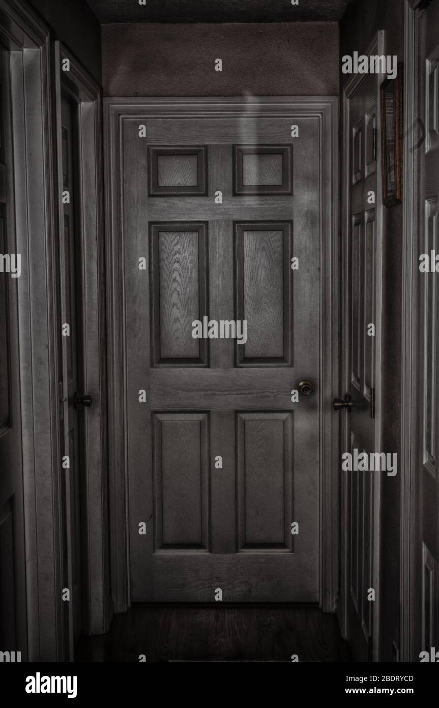 6 panel dingy grungy door leading to who knows where at the end of a hall. Stock Photo