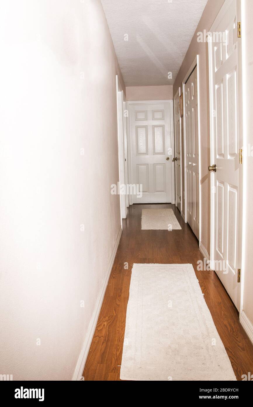 6 panel white door at the end of a long hall.  There are other doors showing as well. Stock Photo