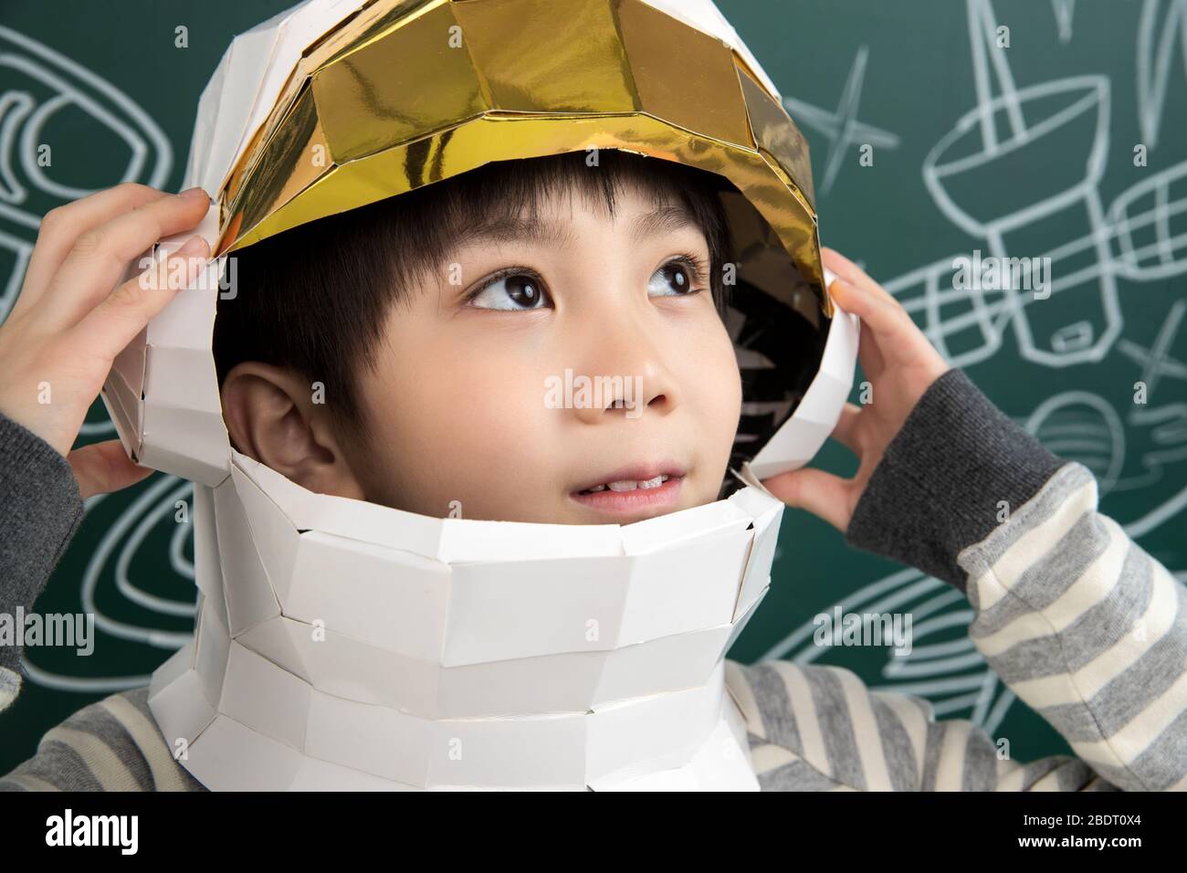 Wearing a helmet of astronauts little boy standing in front of the blackboard Stock Photo